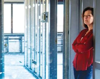 A woman stands in the doorway to a with her arms crossed surveying water damage to her museum.
