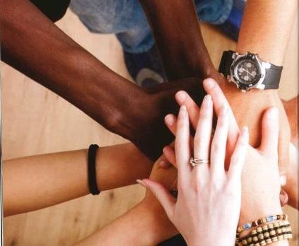 View of a group of different skin tone hands one on top of the other.