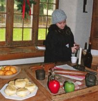 A young teen works with kitchen utensils in a historic kitchen. 