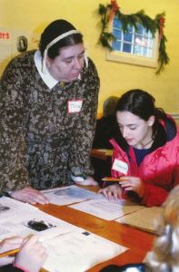 A costumed interpreter looks over a young teen's writing work. 