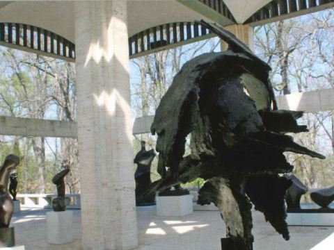 Multiple modern statues stand in a white covered pavilion.