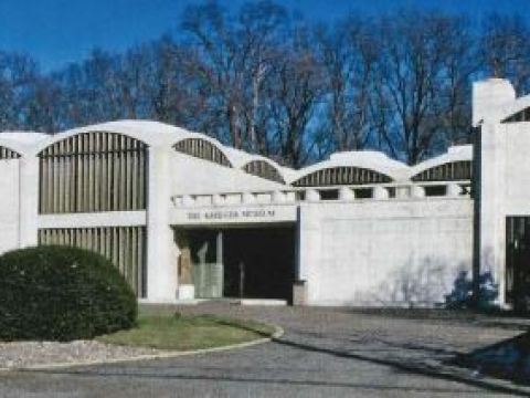 A large white building sits at the end of a circle drive.