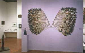 View of an artwork handing on a wall made of feathers looking like wings. 