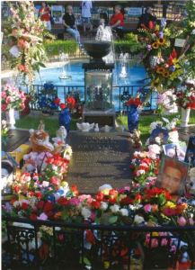 Memorial to Elvis Presley on the grounds of Graceland with flowers and stuffed animals all around it. 
