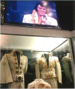 Image of a case at Graceland with two of Elvis' white with gold sequin jumpsuits. 