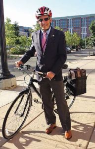 Image of Dr. Adams wearing a bike helmet standing next to his bike. 