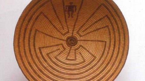 Brown woven basket with a tribal design. The design depicts a man going through a maze.