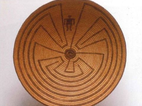 Brown woven basket with a tribal design. The design depicts a man going through a maze.