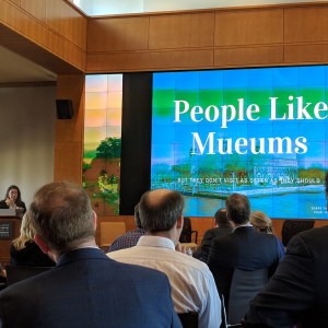 View of the conference room where the historic house summit was held with a group of mainly men looking at a screen with "People Like Mueums" displayed on it.