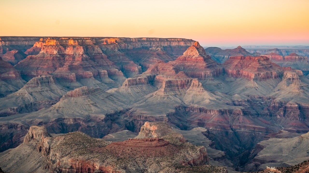 Wide image of the Grand Canyon with lots of oranges and reds.