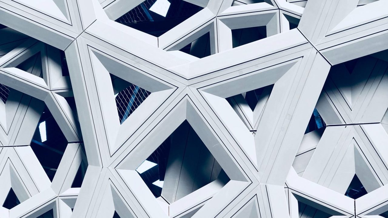 View of a portion of the Louvre Abu Dhabi with intricate interwoven structures and windows framed within.