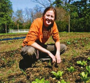 A woman crouches down in a field of growing beans.