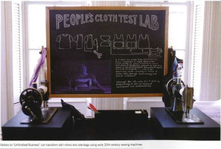 View of two sewing machines with a chalkboard text panel in between them that reads "People's Cloth Test Lab". 