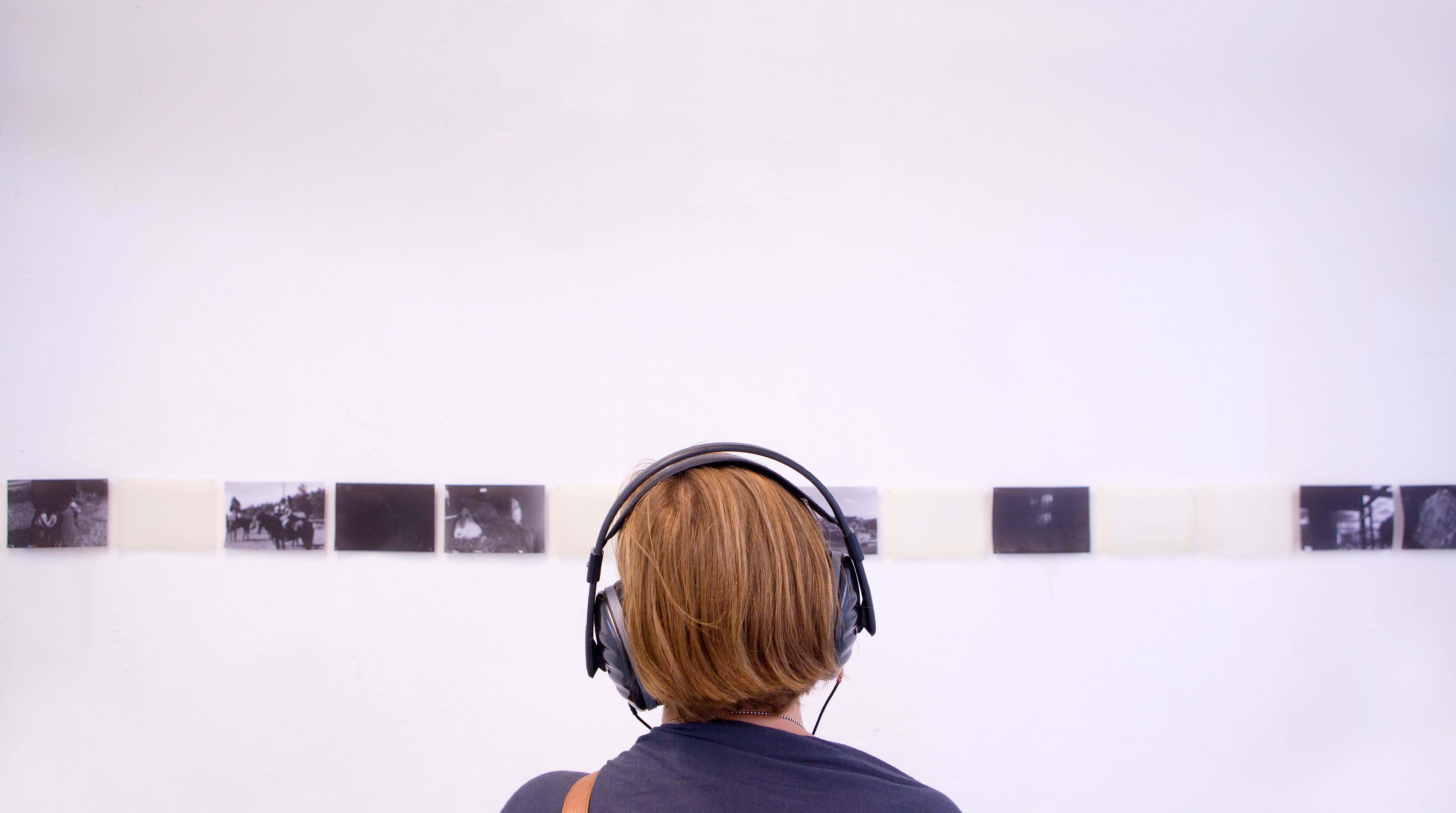 Person wearing headphones looking at photography exhibition.