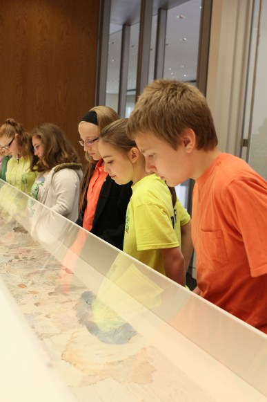 Five middle school students look down into an exhibit case.