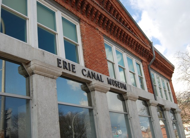 Exterior shot of a red brick and concrete building with Erie Canal Museum in writing on the front.