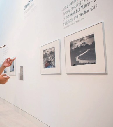 View of a gallery wall with art and someone pointing at the art