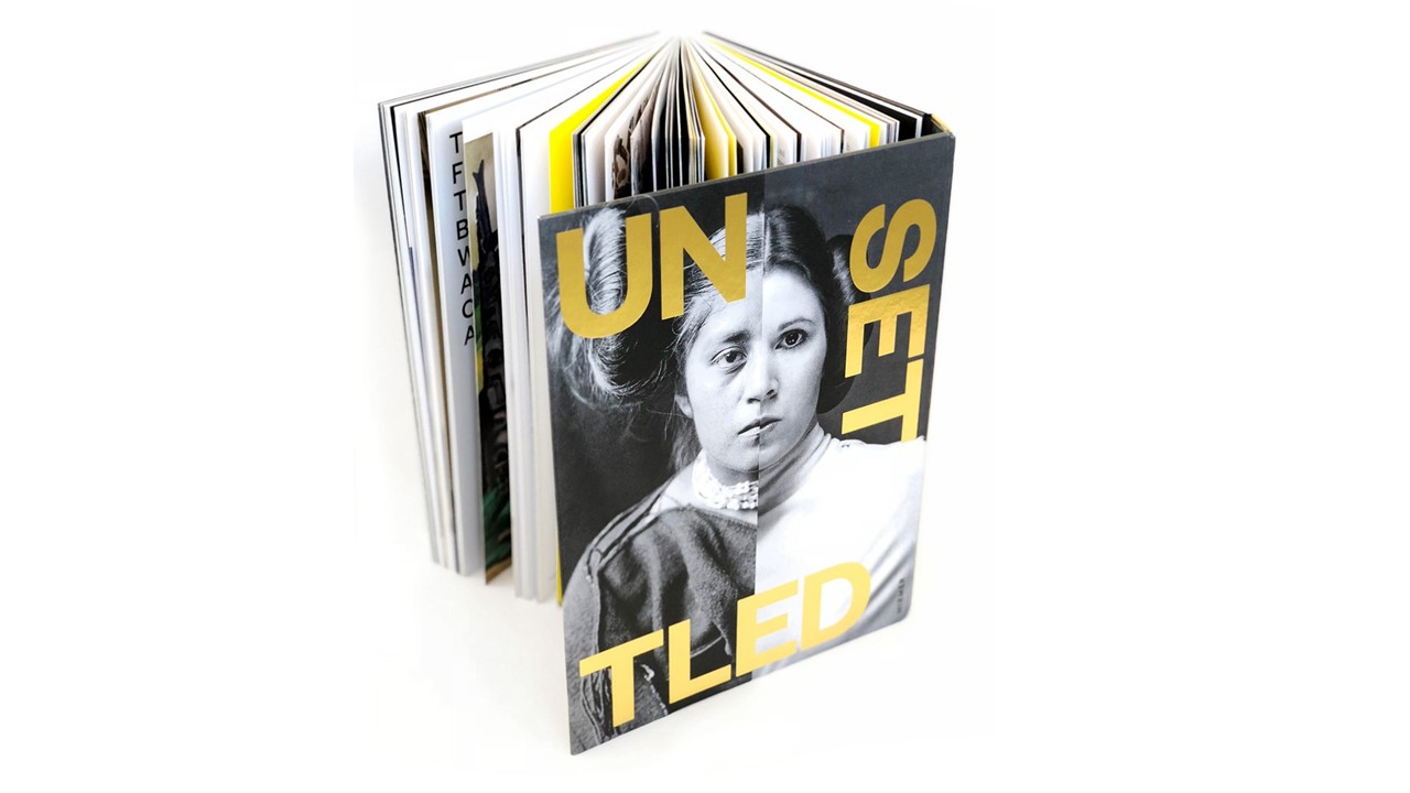 View of the Unsettled book standing open on a white background.