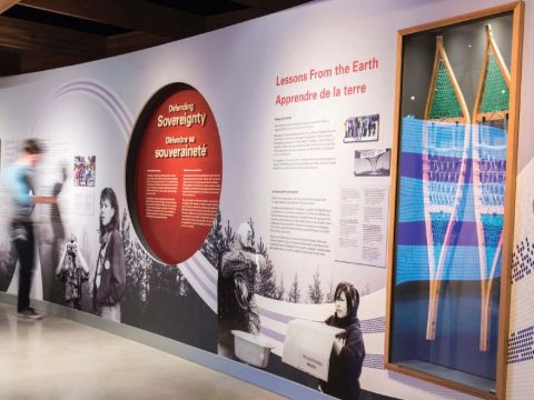 A large wall panel in the exhibit has a snow shoe encased and various black and white images