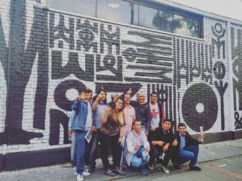 A group of people stand in front of a wall mural posing for a picture. 
