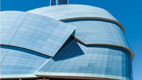 Exterior shot of the museum with overlapping glass structures in the shape of a helmet.