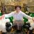 A woman crouches down next to two glass sheep in a fake paddock.