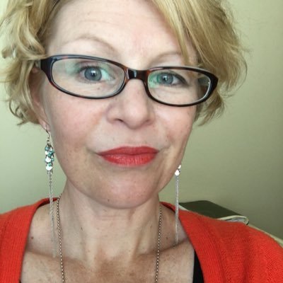 Selfie of a white woman with short blond hair and dark rimmed glasses looking quizzical at the camera.