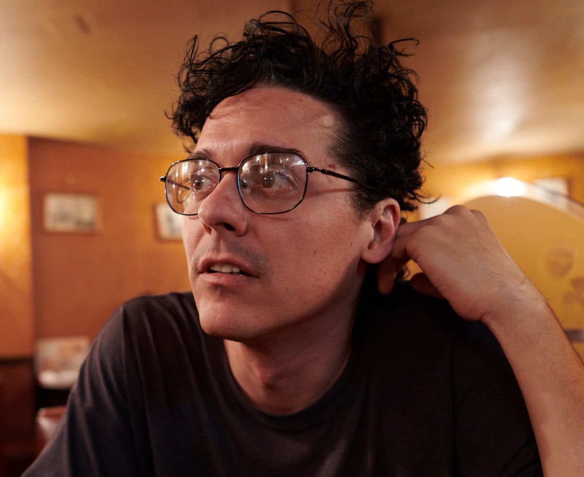 Headshot of a man with wire rimmed glasses and dark wavy hair