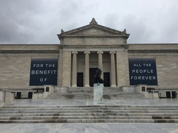 Exterior shot of the facade of the Cleveland Museum of Art, a classical style building with a colunmed portico and wide staircase leading to it.