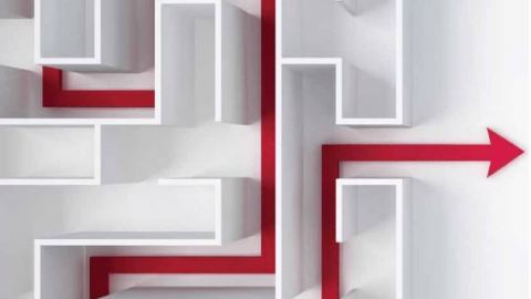Looking down on a white maze with a bright pink line with an arrow on the end going through the maze.