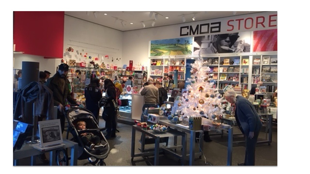Inside a museum store with Christmas decorations and lots of people milling around.