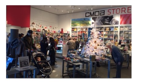 Inside a museum store with Christmas decorations and lots of people milling around.