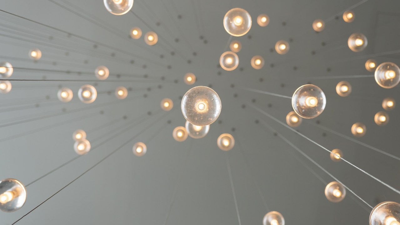 Looking up at light bulbs hanging from the ceiling by wire.