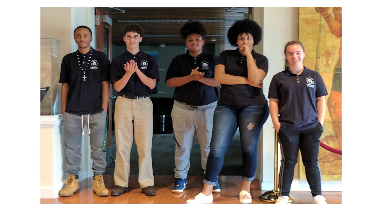 A group of five teens stand in a doorway posing for the camera.