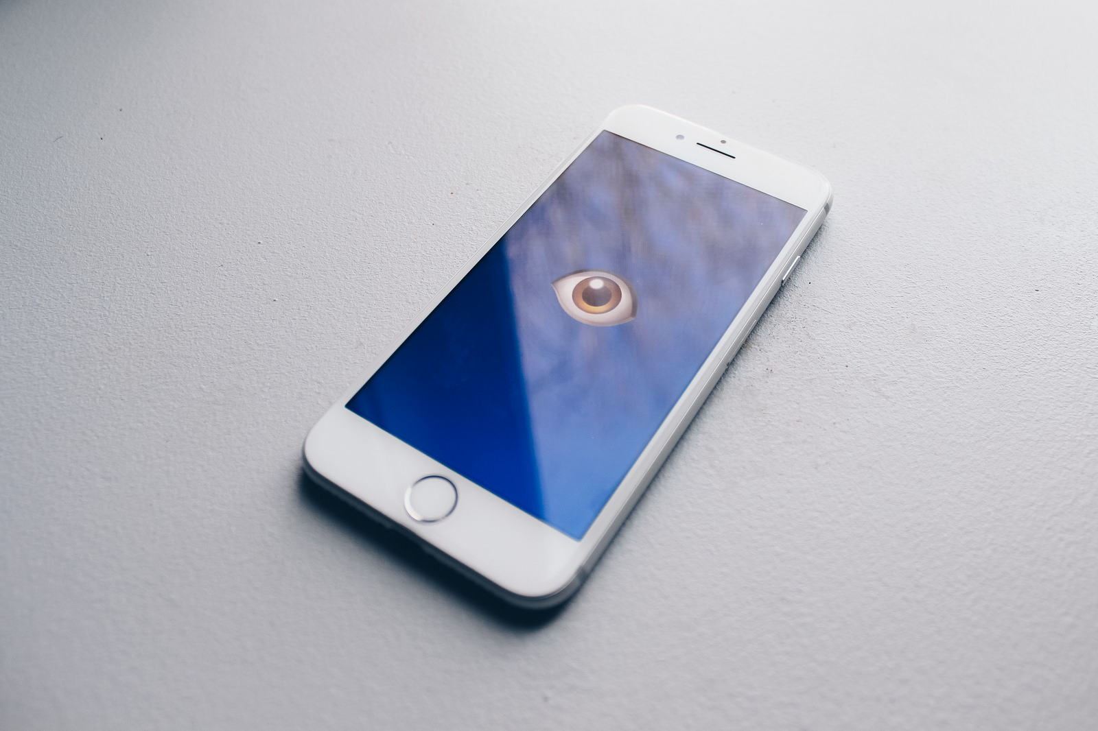 A smartphone sits on a flat surface. On the screen is a drawing of a single eye, an illustration of the privacy issues that modern technology can pose.