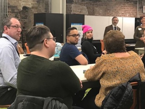 Eight members of CAMP are shown seated around a conference table attending a breakout session at a CAMP meeting where they discussed challenges with LGBTQ inclusion at museums and potential solutions to them.