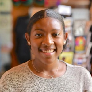 Headshot of Ashleigh Smith, a young black woman with her dark hair pulled back wearing a light colored sweater and smiling at the camera.