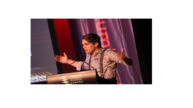 Man wearing suspenders speaking behind a podium
