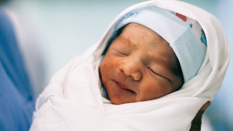 Image of a newborn baby swaddled in a white blanket.