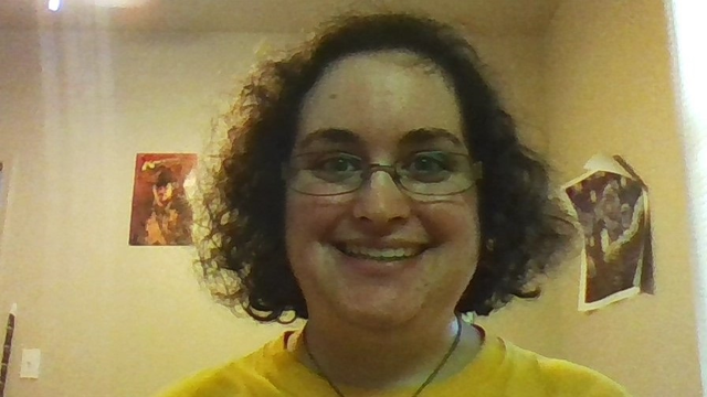 Headshot/selfie of Samantha Silverberg smiling at the camera with short brown hair wearing wire rimmed glasses.