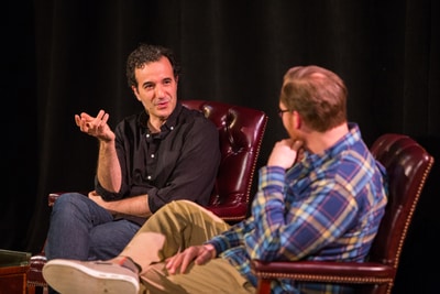 Two men seated and having a conversation on stage.