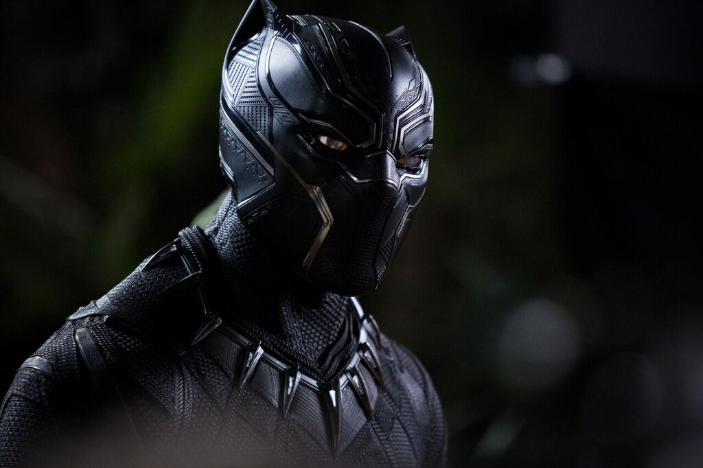 A still photograph of the Black Panther character T'Challa in superhero costume, which is black, sleek, and spiky.