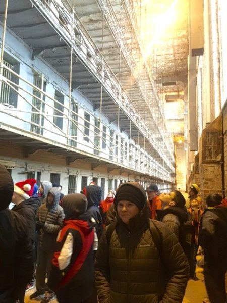 The teacher is seen standing with students in front of an exhibit of a block of living spaces.