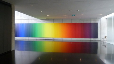 A rainbow colored artwork installed in a museum
