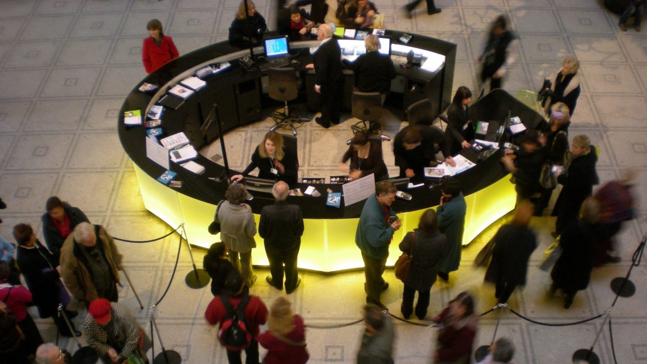 A crowded circular information desk in a museum lobby.