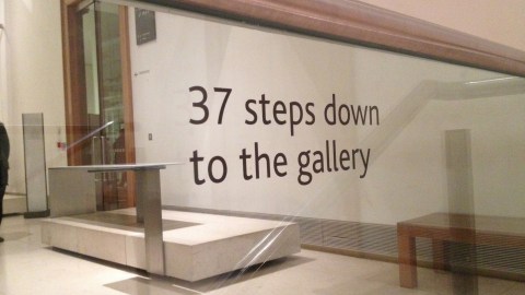 At the top of a staircase in a museum, a sign advises that there are "37 steps down to the gallery."
