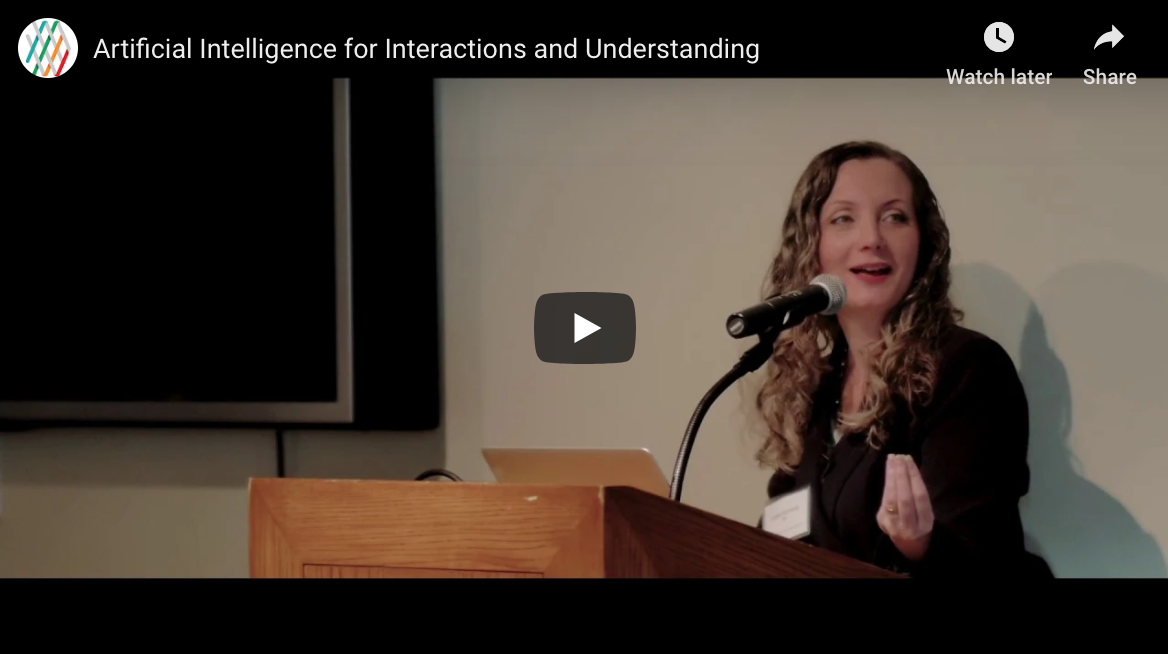 Screenshot of the YouTube video Kristen Summer's presentation. The image shows Summers smiling and gesticulating from behind a podium.