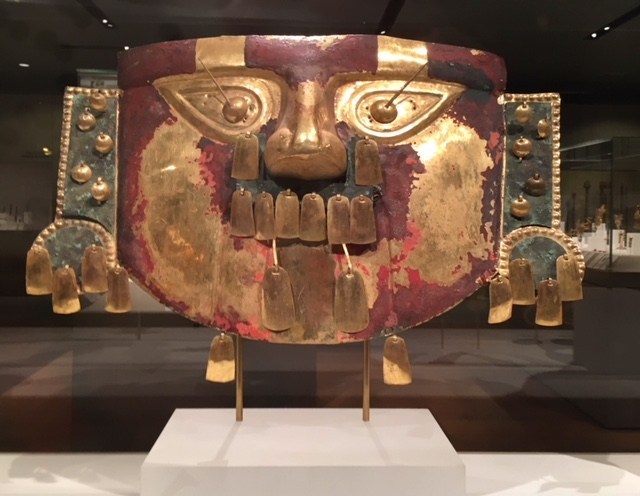 A gold Peruvian mask of a stylized face