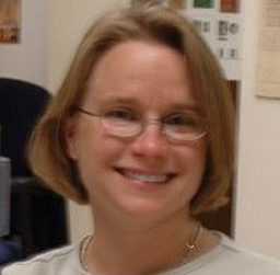 Headshot of Donia Conn, a white woman with short blond hair wearing wire rimmed glasses.