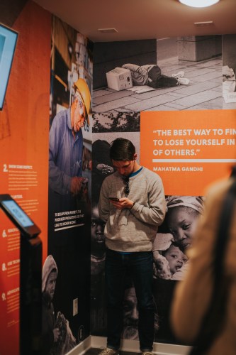A visitor in the museum stands in front of a quote on the wall from Mahatma Gandhi.